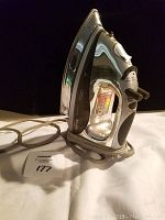 View of the Shark iron standing upright showing the handle and cord wrapped around the base.