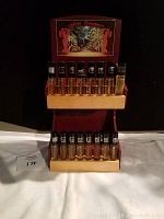 Front view of 20 small YAKSHI fragrance bottles on a wooden stand with decorative backdrop