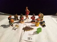 Overview of 11 assorted figurines including 4 African American basketball player figurines and decorative animal and novelty pieces against a black background.