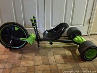 Side view of Huffy Green Machine tricycle bike showing large front wheel, bucket seat, and smaller rear wheels.