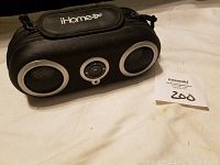 Front view of black iHome 2Go portable speaker with carrying case showing two speaker grills and central control button with iHome 2Go branding.