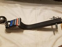 Side view of the UHAUL PowerTow drawbar showing the full length, black metal with attached pin and clip.