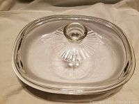 Top view of the clear glass rectangular Corning Ware baking dish with lid on, showing the lid knob and ribbed design on lid.