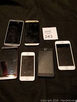 Top view of the 6 smartphones laid on black fabric background with a MaxSold bidder card visible