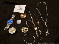 Overview of lot items including coins and jewelry pieces arranged on black cloth
