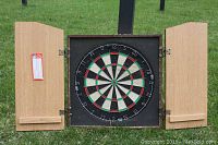 Wooden dart board cabinet open with dart board inside showing traditional numbered segments in red, black, white and green.