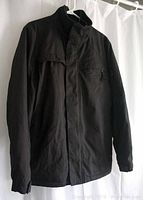 Front view of men's black Calvin Klein jacket, size small, showing the pouch pocket details and high collar with button flap closure.