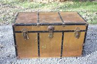 Front view of the vintage storage chest showing the brown body with black trim and central metal latch.