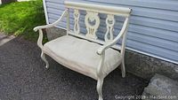 Front angled view of wooden bench with curved arms and upholstered seat