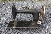 Side view of the vintage New Home black sewing machine showing worn black paint and metal sewing plate