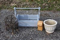 Four items placed outdoors on gravel - decorative twig sleigh, blue wooden basket, wooden knife block, white ceramic plant pot
