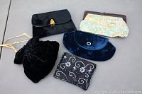 Front view of all five vintage clutch purses arranged on a flat surface showing different styles and materials.