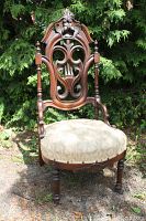 Full view of antique wooden chair showing carved backrest and upholstered seat.