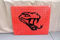 Front view of red metal snake head wall decor showing black snake head design with circular holes