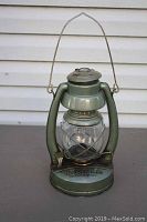 Full view of the green metal Embury Air Pilot oil lantern showing intact glass globe and metal handle.