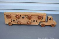 Front view of the wooden toy transport truck with the three nested wooden toy cars in its trailer.