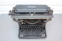 Front view of black Underwood typewriter showing wide body, keyboard, and type bars.