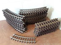 Stacked curved and straight O scale Lionel train tracks showing overall quantity and condition with some rust and broken rails visible.