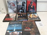 Photo showing eight DVD cases with visible cover art, including Jurassic Park series, Exit Wounds, Stallone's Cobra, Boiling Point, Space Cowboys, K-PAX, and Independence Day.