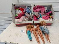 Four vintage Barbie dolls laid out in front of two boxes filled with assorted doll clothes and accessories