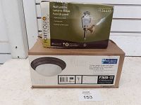 Two boxed light fixtures: Portfolio wall lantern box on top with visible box damage; Progress Lighting flush mount light fixture box below.