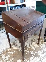 Full view of antique wooden writing desk showing hinged top, brass hardware, and decorative inlay.