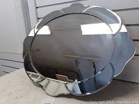Front view of an oval mirror with a scalloped edge frame, showing reflective surfaces and the mirror's design