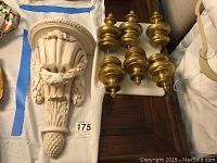 Photo showing one decorative carved wall corbel shelf with ribbon and acorn design along with 6 gold-toned curtain rod finials.
