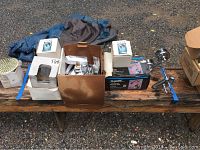 Full view of all items on wooden bench, including boxed plumbing parts and loose chrome plumbing components plus a blue jacket.