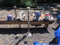 Full view of all candle holders and vases placed on a wooden bench outdoors, showing size and variety.
