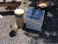 Photo showing all three items: cream milk can with blue floral design, small silver metal trash can, and a decorated wicker basket box with blue top and painted motifs.