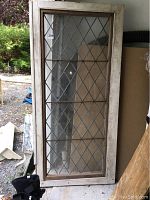 Full view of the vintage glass window pane leaning against a wall, showing overall size and condition of the wooden frame and glass.