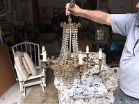 Photo showing the crystal chandelier held up, multiple tiers of hanging crystal beads, six candle lights around the perimeter.