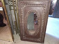 Rectangular mirror with ornate metallic frame, oval beveled central mirror