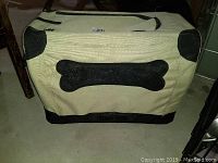 Soft-sided beige and black pet carrier with bone shape decoration, fabric material