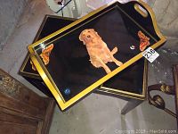 Rectangular tray with dog and butterflies motif placed on black gold-trimmed table, angled top-down view