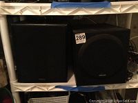 Two boxed speakers side by side on a shelf, one Advent and one Polk Audio.