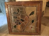 Framed stained glass panel front view showing floral design with purple and white flowers and green leaves.