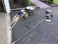 Full garden lot showing scarecrow, two bird feeders on poles, green pot, iron stand, cast iron owl, brass planter, and granite dish