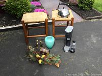 Two rattan stools with woven seats, kettle on stool, soda maker and bottle next to stools, teal vase, brass cats, decorative artificial fruit display, wooden box with inlay and felt lining