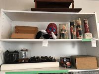 Shelf with vintage Dutch dolls in protective tubes, a large red doll face, and other items including a toy truck and small collectibles