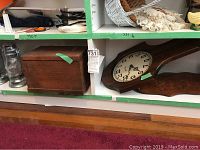 Wood box, wood sconces, battery lanterns, and Bulova wall clock arranged on shelves and carpet