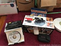 Nikon Coolpix S3000 box, Polaroid 600 camera box, Polaroid 600 film box, 8GB SD card, Staples shredder box on floor.