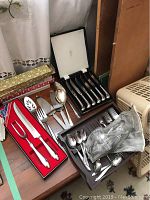 Overall shot showing multiple flatware items including knives, spoons, forks, and a boxed set.