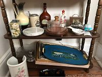 Shelf with covered cheese plate, stone cheese dish, pitchers, spoon rest, napkin holders, and vintage trays
