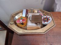 Brass tray containing lighters and various compact and hand mirrors, plus small decorative items.