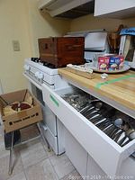Vintage wood storage box on stove, closed and open with flatware inside