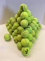 Pyramid stack of 75 used yellow-green tennis balls, clearly showing various brands including Wilson, some with green dot markings.