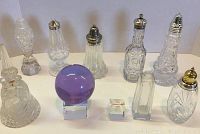 Overview of all 10 vintage glass vanity items including bell, purple glass ball, small bases, bottle, and six powder shakers with metal tops.