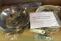 Cookware components including glass lids, metal pans, silicone whisk and grips packed in box.